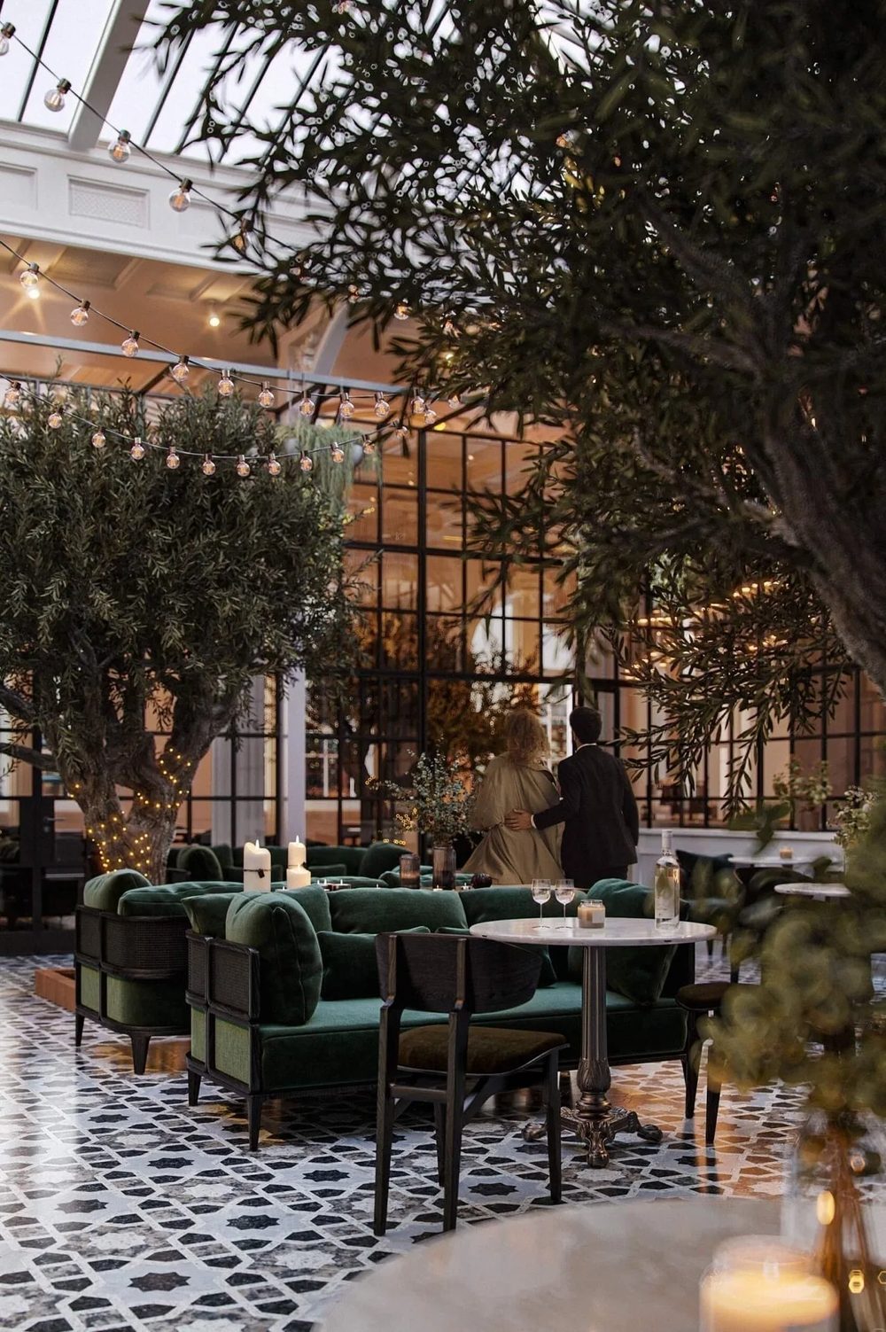 3D visualization of a restaurant interior with green velvet chairs and olive trees