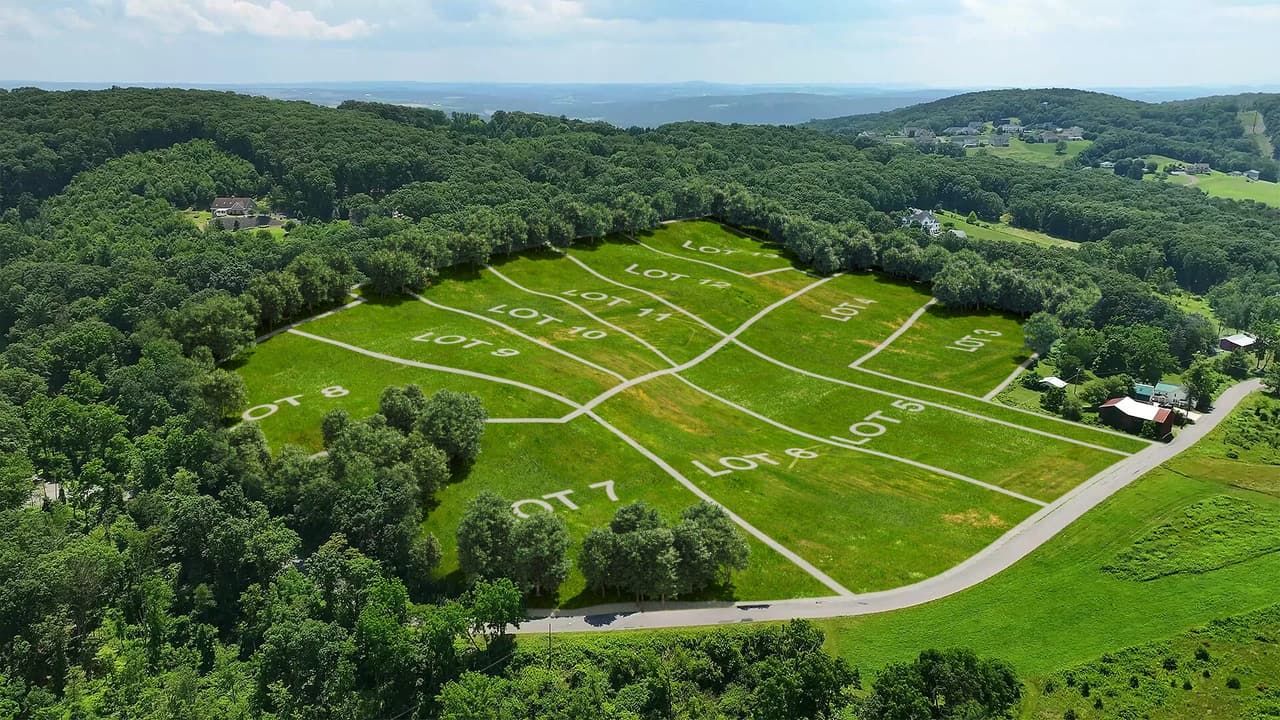 Aerial site plan rendering showing 12 numbered lots with boundary lines overlaid on drone footage of undeveloped land in Danville, PA
