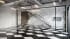 3D visualization of a modern building lobby with checkered marble flooring, floating staircase, and exposed ceiling ductwork