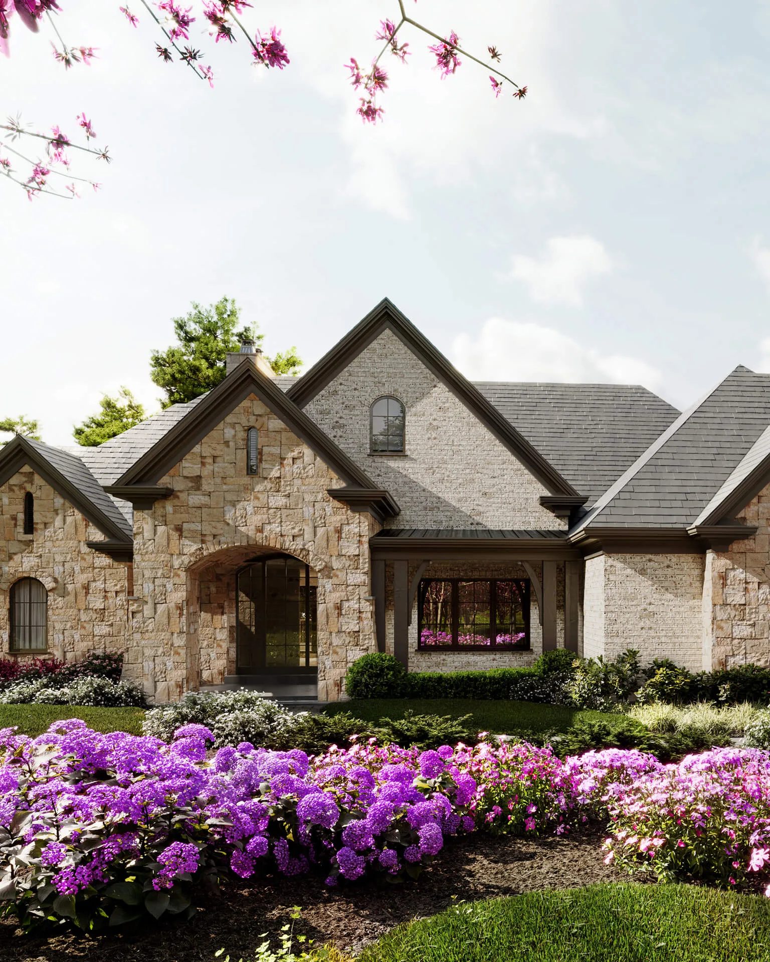 Family house with a garden: stone clad home behind flowering beds in bloom