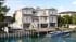 CGI of a three-story shingle-clad waterfront house with a pool, private dock, and speedboat in New Jersey