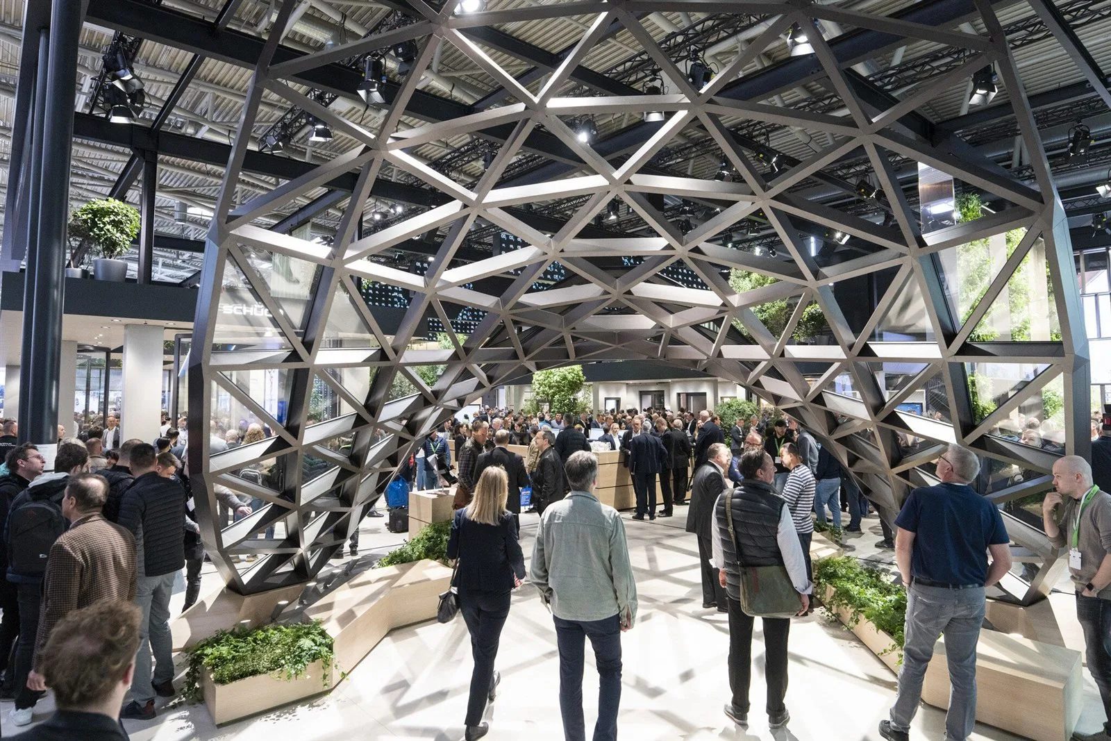 Visitors walking under a steel and glass arch in a hall at BAU, Messe München