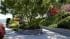 3D rendering of a sunlit garden path at a Lake Como villa, with a curved stone flower bed, mosaic paving trim and flowering trees