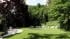 Landscape 3D render of a villa lawn with a round lily pond, fire pit lounge, tiered fountain and bamboo grove near Lake Como