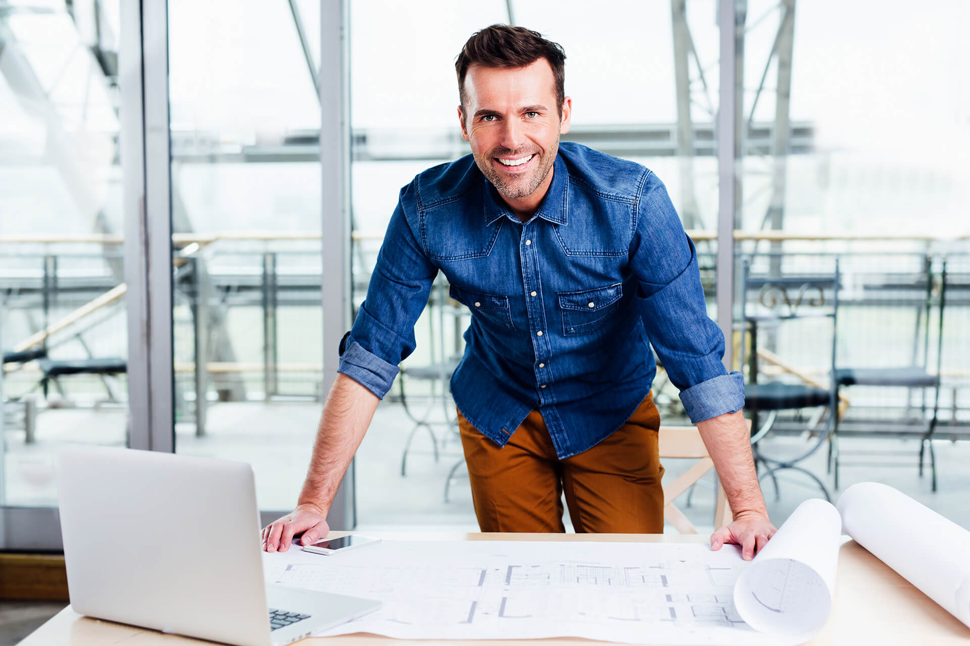 An Architect Standing over Drawings at the Office