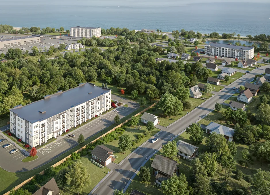 A low rise apartment building sits beside a road and parking area in a green suburban setting in 3D rendering.