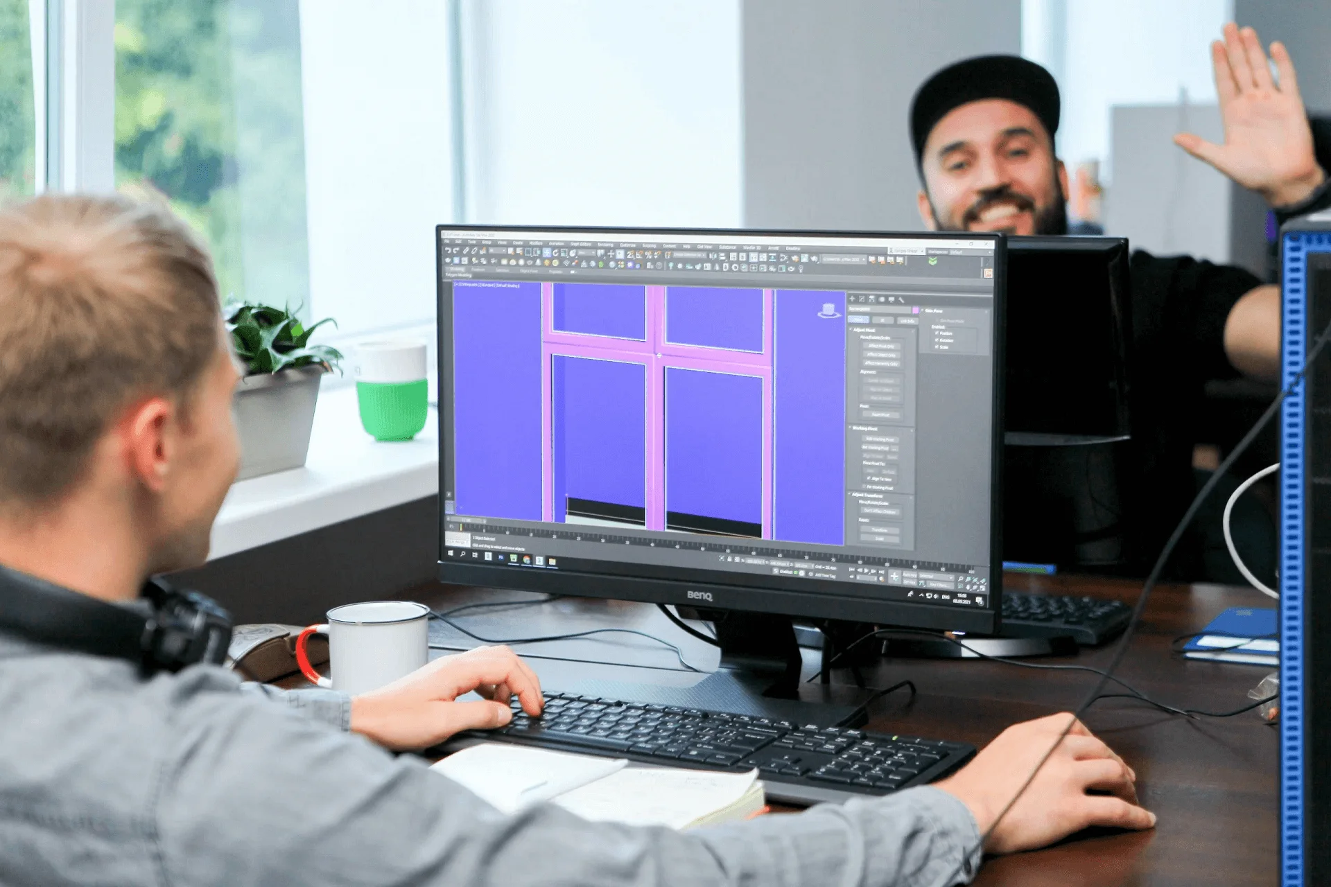 Two 3D artists collaborating at a workstation in a CGI studio