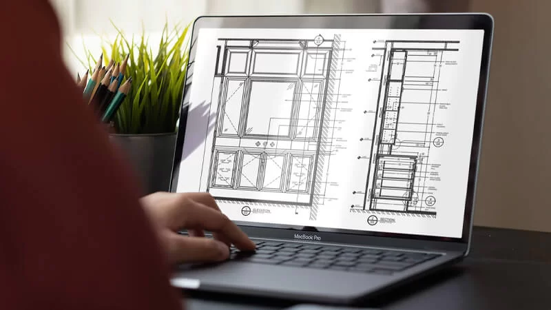 Cabinetry shop drawings for a Vancouver interior project on a laptop beside a desk plant