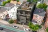 Architectural 3D visualization of a modern dark-clad multifamily building with glass facades, rooftop terrace, and balconies seen from an aerial perspective in an urban residential neighborhood